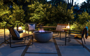 A lit fire pit at night with surrounding chairs